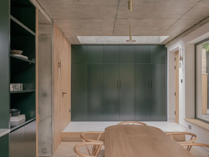 Interior view of green storage wall and raised platform beneath concrete ceiling with brass pendant