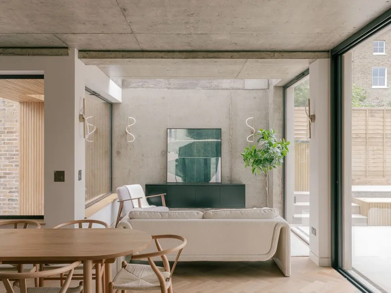 Living area with exposed concrete beam ceiling and green cabinetry below abstract painting on rear wall