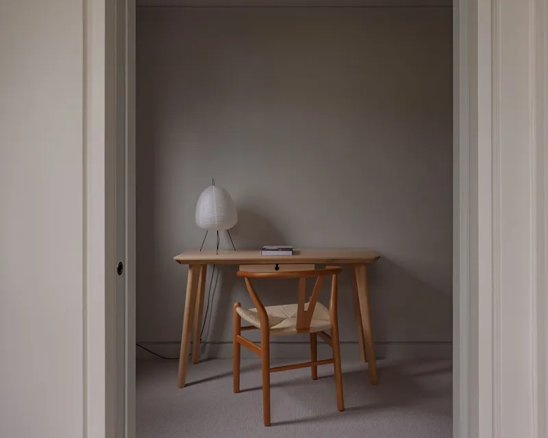 Timber desk with chair and table lamp viewed through white painted doorway