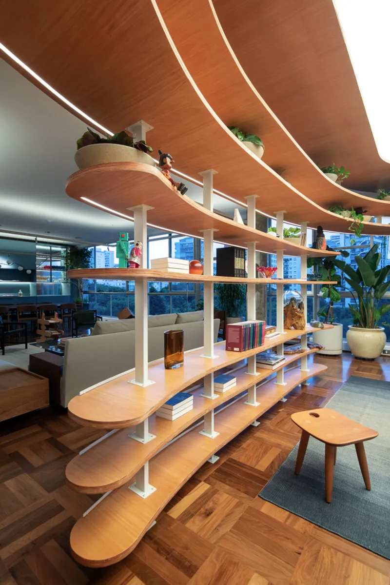 Curved timber shelving partition with white supports beneath wood-clad ceiling and linear lighting