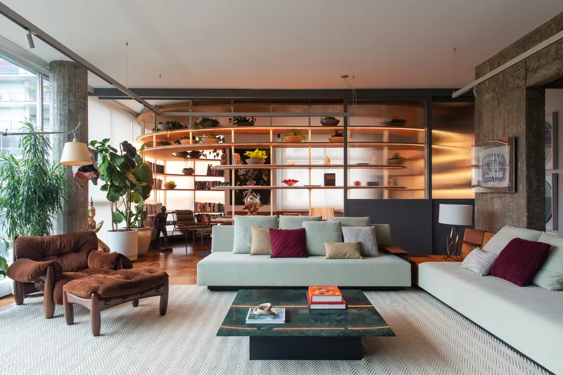 Shelving wall with integrated lighting at dusk, casting warm glow across seating area