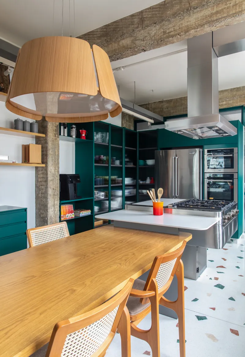 Open kitchen with teal shelving, stainless steel island, and exposed concrete beams under a wood veneer pendant