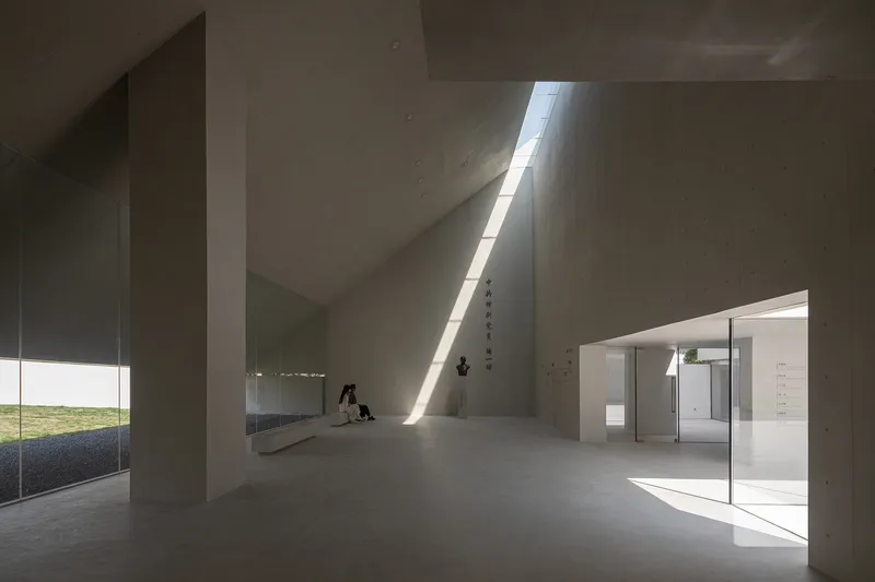 Interior gallery with concrete walls and a narrow skylight casting sharp daylight across the floor