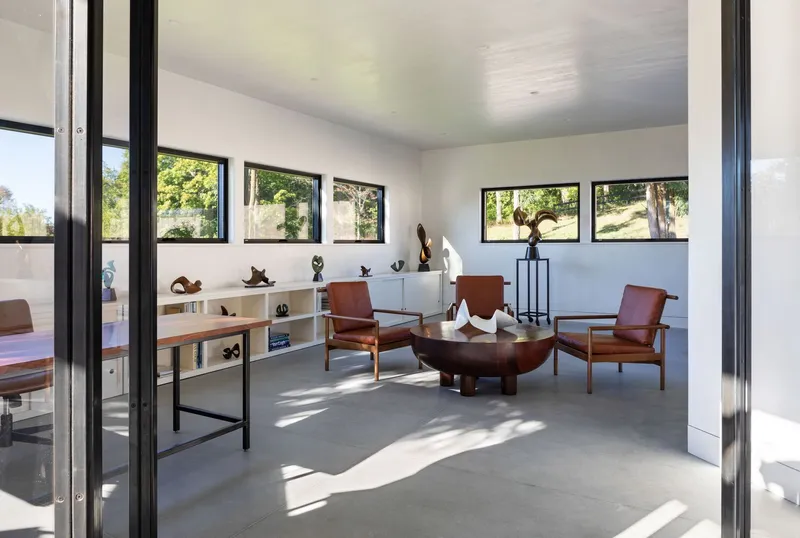 Living space with polished concrete floor and horizontal window band framing views of grazing sheep outside