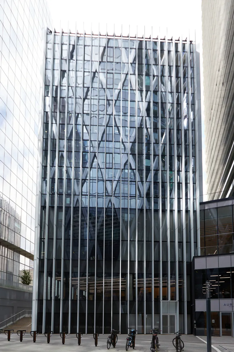 Glass and metal facade with diagonal bracing pattern viewed from the plaza with pedestrians below