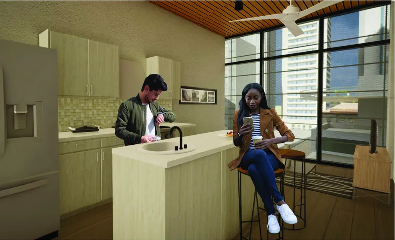Compact kitchen with light wood cabinetry, white countertop and two people inside