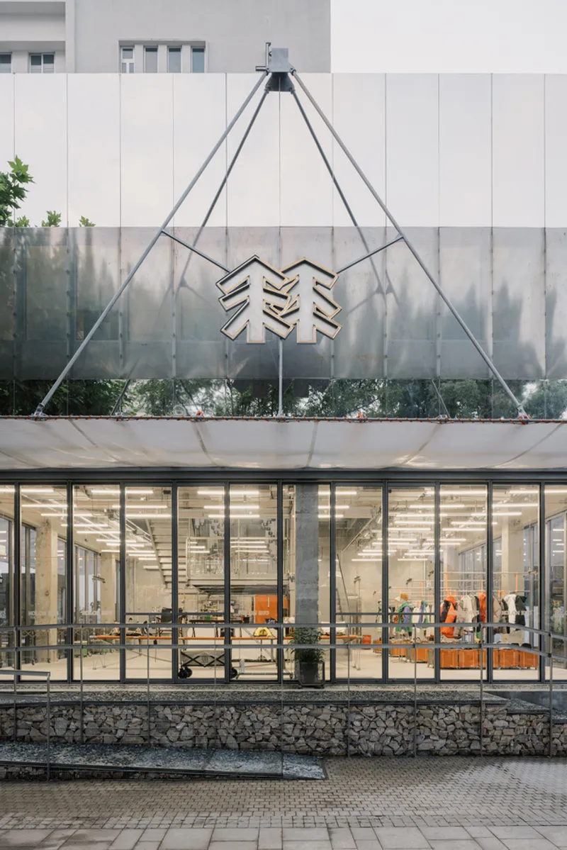 Tensile steel cable structure supporting a symbolic metal sign above the glazed entrance facade