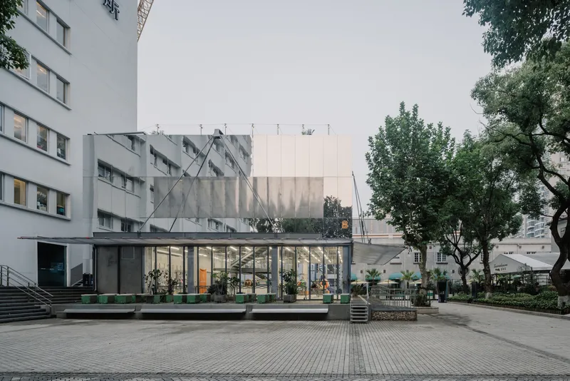 Courtyard view of the glazed pavilion with cable-supported roof between existing residential towers and trees