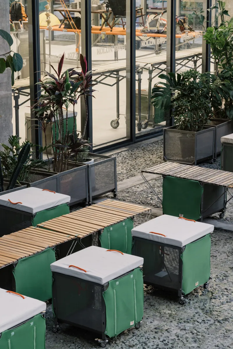 Green modular benches with timber slat surfaces and metal planters on terrazzo flooring