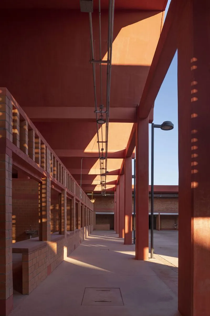 Colonnade with steel beams and light strips creating diagonal shadow patterns at sunset