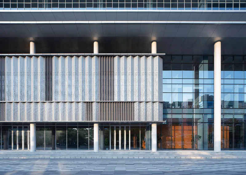 Close view of the corrugated precast panel wall with cylindrical columns and glazed entrance behind