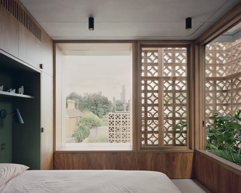 Bedroom with walnut-clad walls and sliding lattice panels framing a view to the treetops