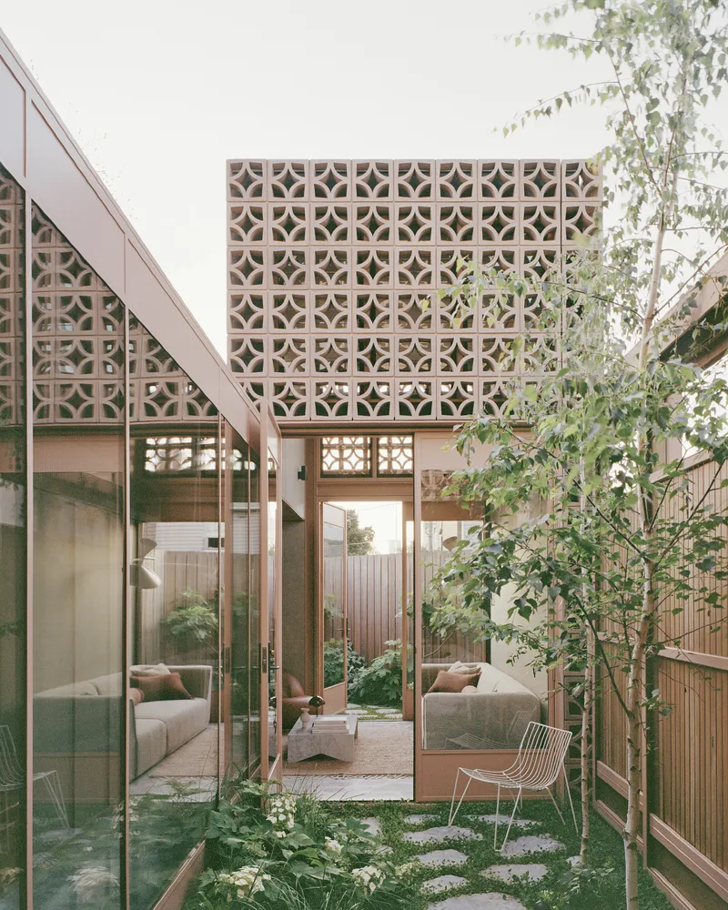 Courtyard garden with patterned breeze block facade and young birch trees among stepping stones