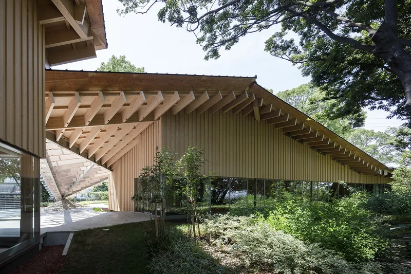 Covered entry with exposed timber rafters and vertical wood slat cladding under tree canopy