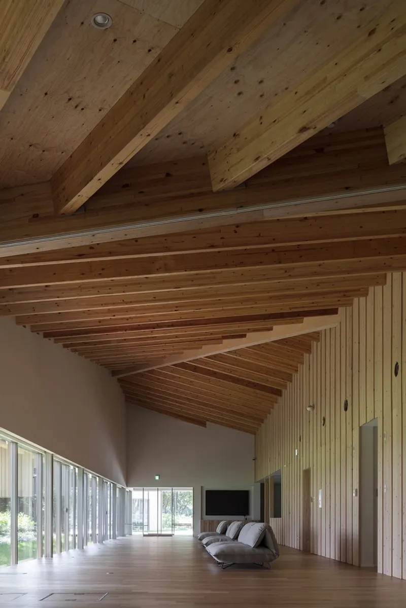 Interior space with exposed timber beams and rafters spanning a white-walled living area with timber flooring