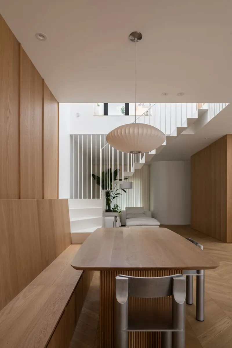 Dining area with timber joinery and saucer pendant light looking toward the staircase with vertical screens