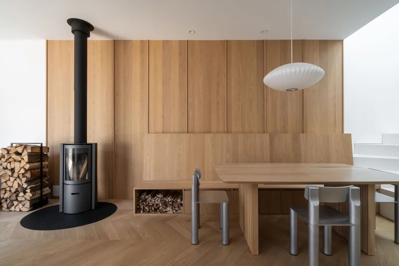 Dining area with vertical timber wall paneling, freestanding wood stove and herringbone oak flooring