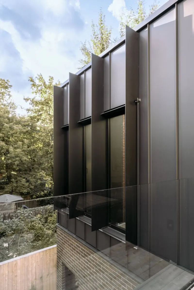 Exterior view of the dark metal cladding facade with vertical fins above a timber deck