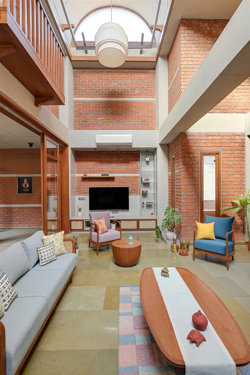 Double-height living room with exposed red brick walls and arched skylight above a spherical pendant lamp