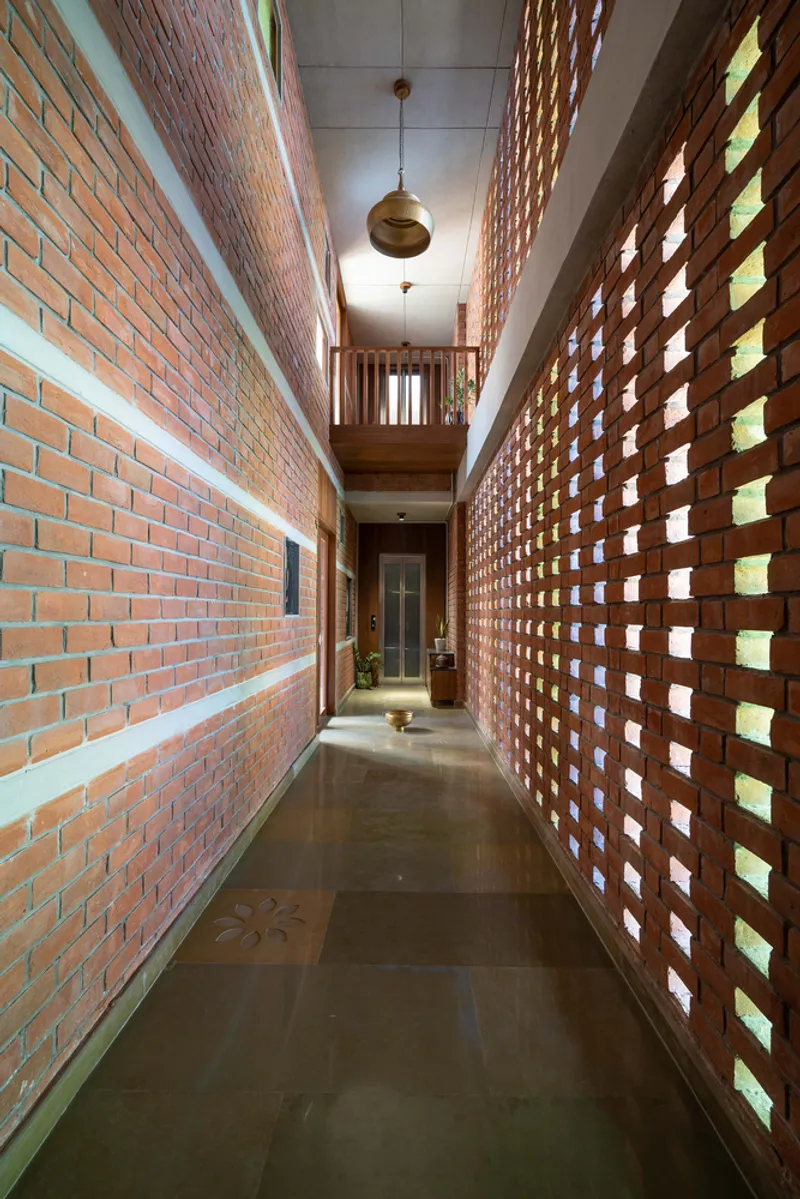Corridor flanked by perforated brick screen wall with glass block openings filtering daylight through