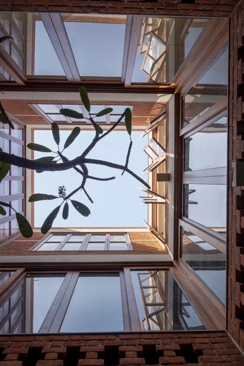 Looking up through the open courtyard with timber-framed balconies and a plumeria tree overhead