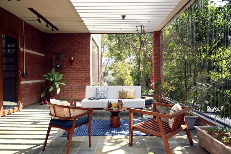 Covered terrace with seating area overlooking garden through vertical cable railing under slatted pergola