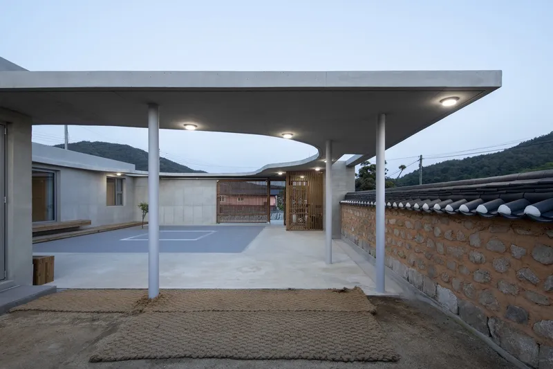 Covered entry canopy with slender white columns and recessed lighting at dusk