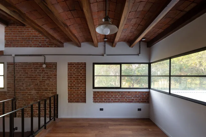 Upper-level room with brick vaulted ceiling and corner window overlooking landscape