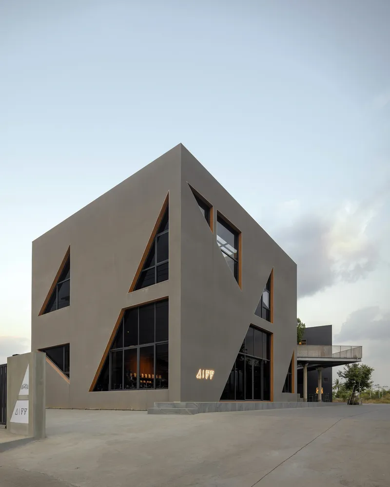 Street view of the concrete facade with angular cut-out windows at dusk