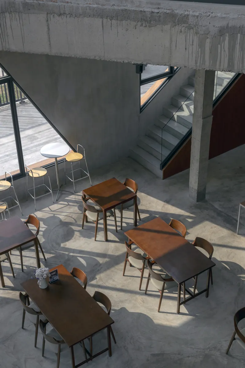 Overhead view of concrete stair and dining area with sunlight casting shadows across the floor