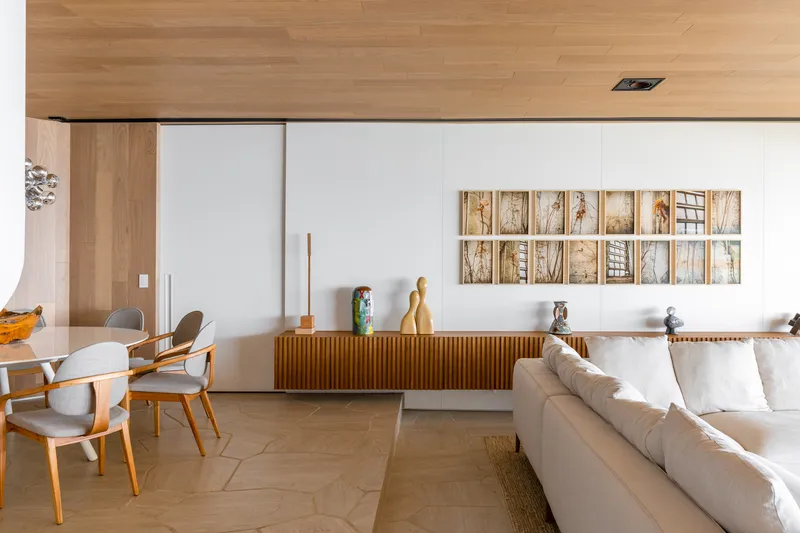 Living room with timber credenza and white walls displaying a grid of framed photographs