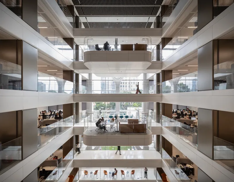 Interior atrium with staggered white floor plates and people working at desks on multiple levels