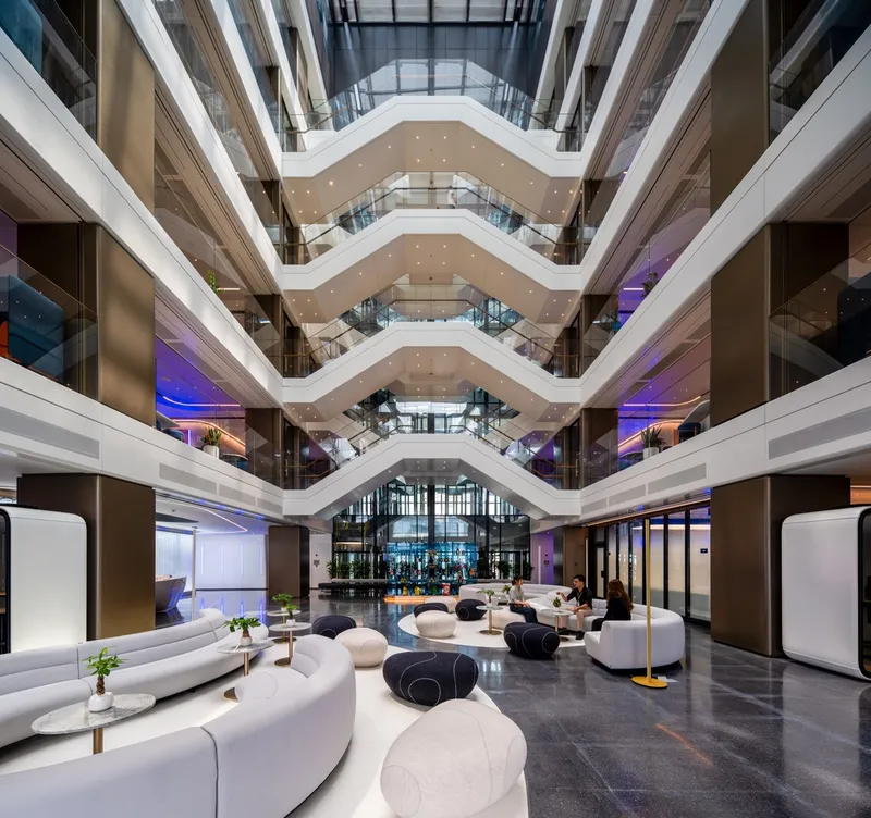 Ground floor lobby with curved white seating beneath chevron balconies and purple accent lighting