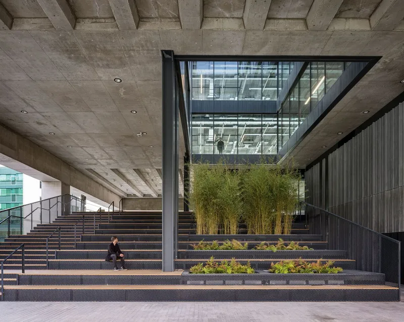 Tiered seating steps with integrated planters and bamboo beneath a coffered concrete ceiling