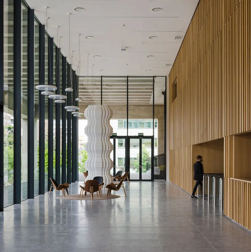 Polished concrete lobby floor with timber slatted wall and a blurred figure walking past