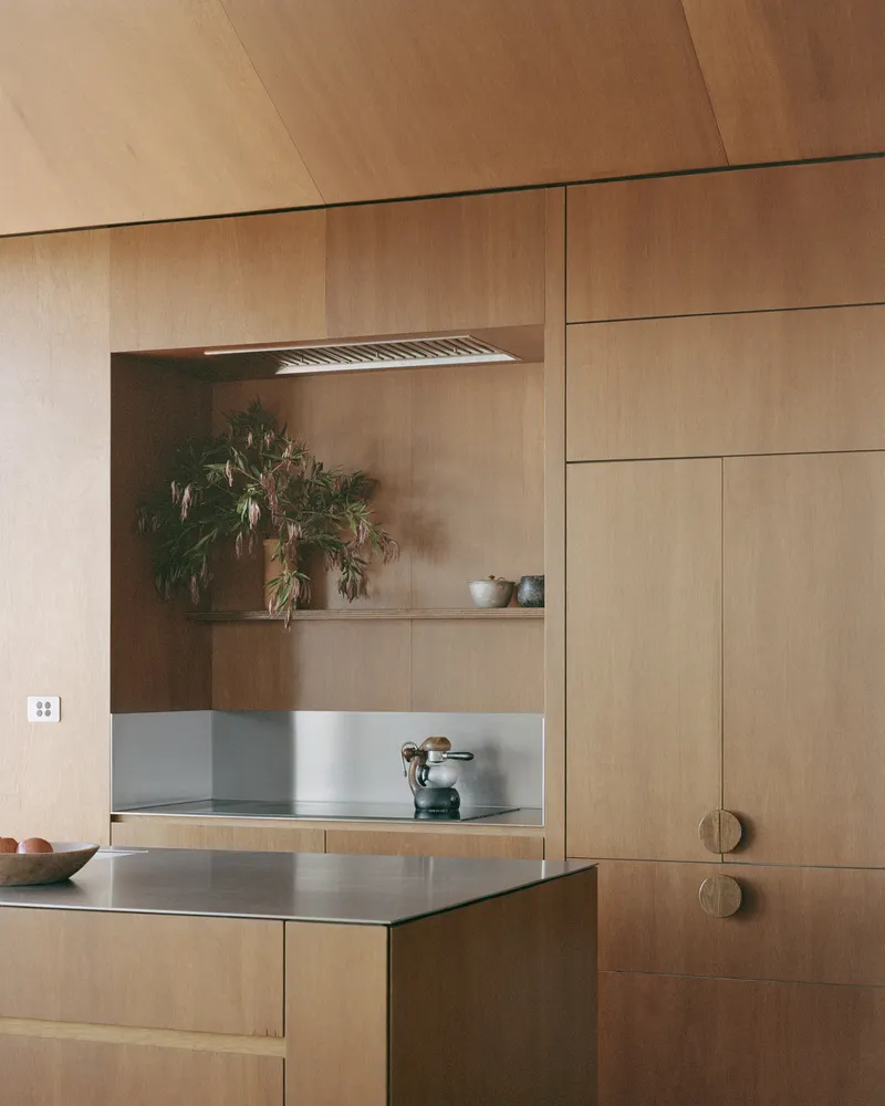 Kitchen wall detail with recessed plywood niche and stainless steel countertop island