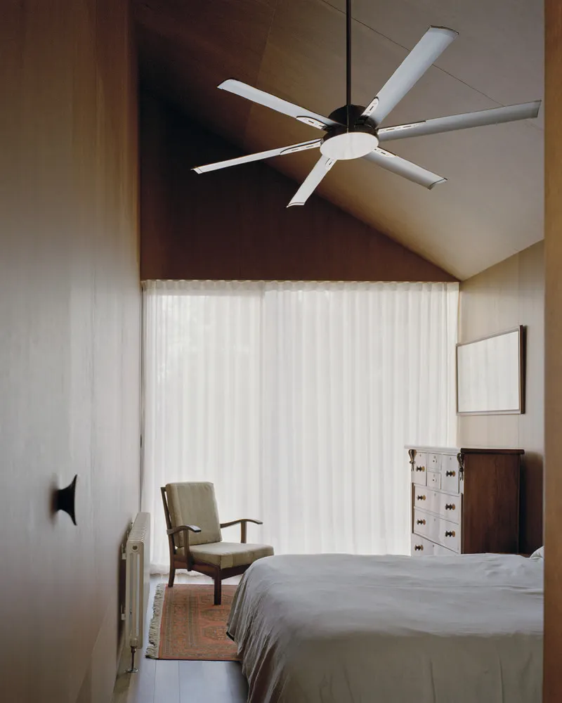 Bedroom with vaulted plywood ceiling, ceiling fan, and sheer curtains filtering daylight