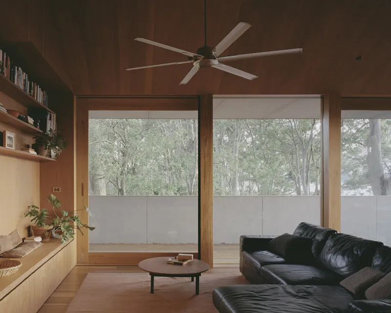 Living room with timber-lined ceiling, ceiling fan, and glazed doors opening to a snowy courtyard
