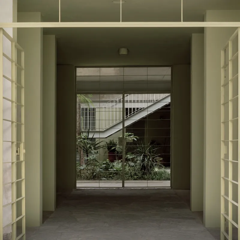 Glass block wall framing a view through to the planted courtyard and diagonal staircase beyond