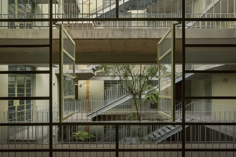 Gridded window view into the central courtyard showing circulation bridges and a slender tree