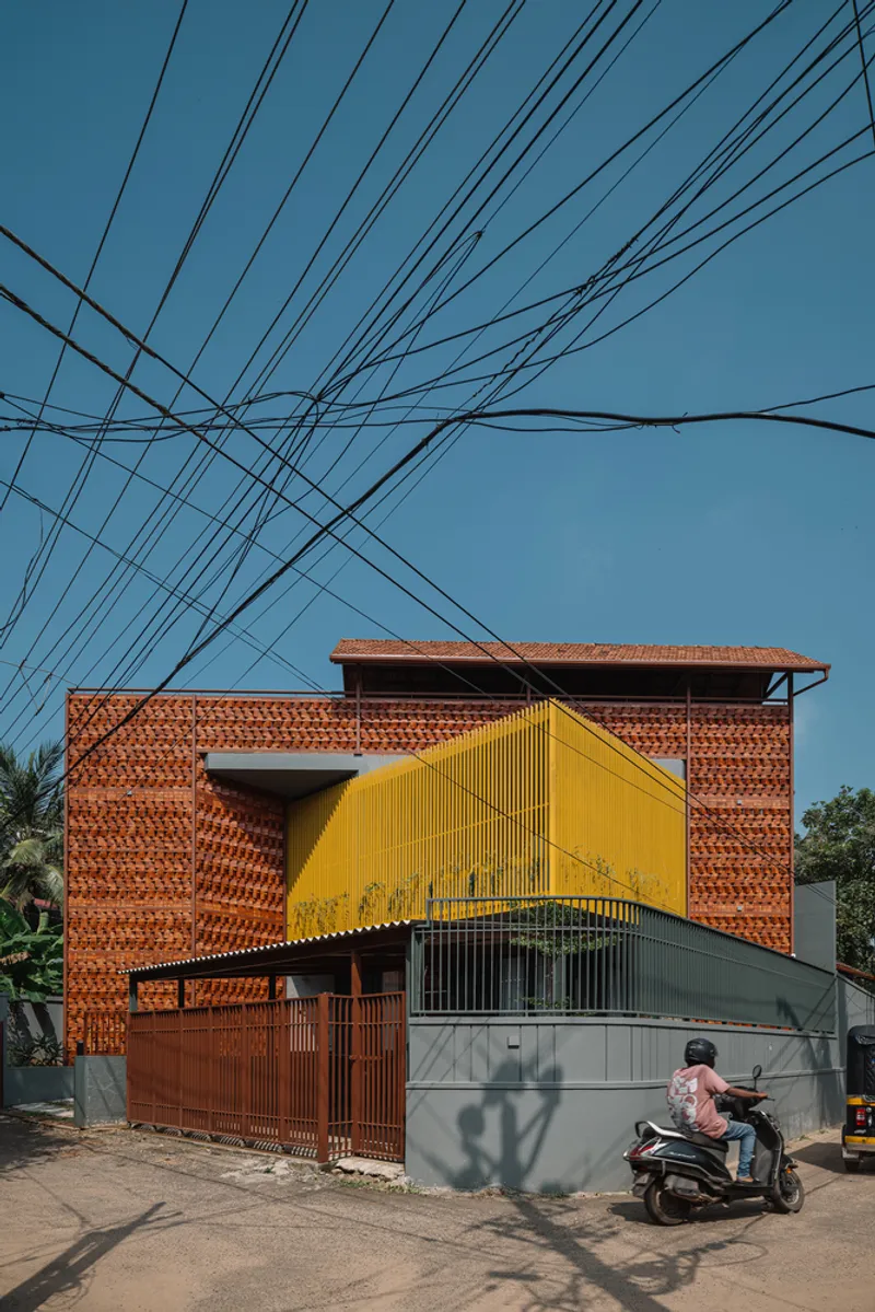 Street view of the patterned terracotta brick facade with yellow metal screen and overhead power lines