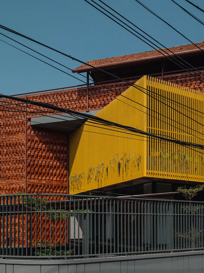 Close view of the yellow louvered screen above grey metal perimeter fencing crossed by power lines