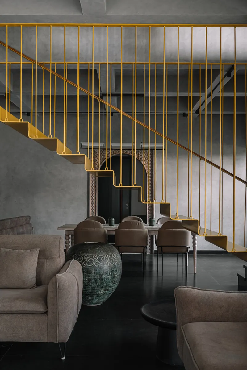 Yellow steel staircase with vertical railing ascending from the double-height living space