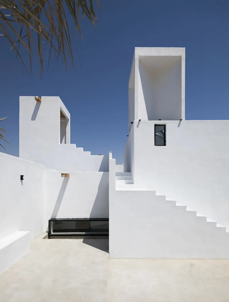 White exterior stairs connecting multiple levels with palm fronds visible overhead