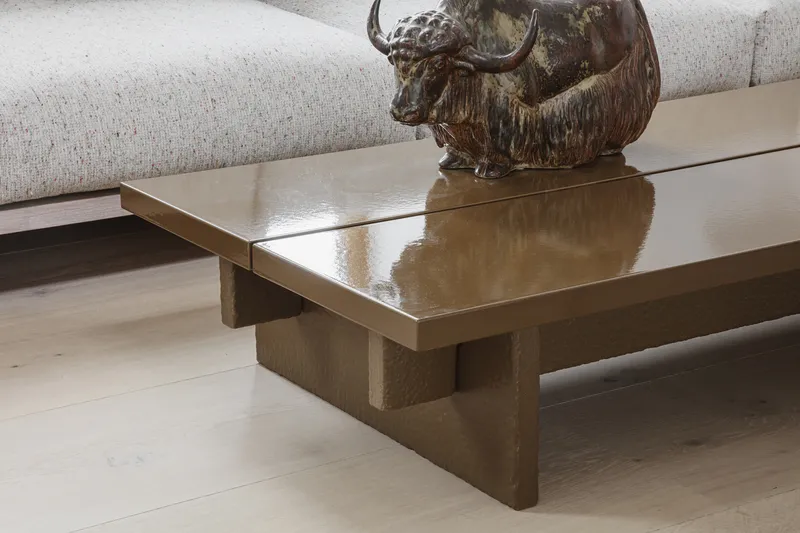 Bronze coffee table with stone base and bronze sculpture on light timber flooring