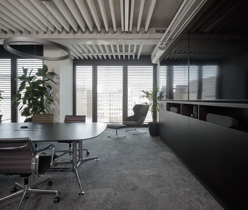 Office area with white ceiling baffles, potted plants and windows with horizontal blinds