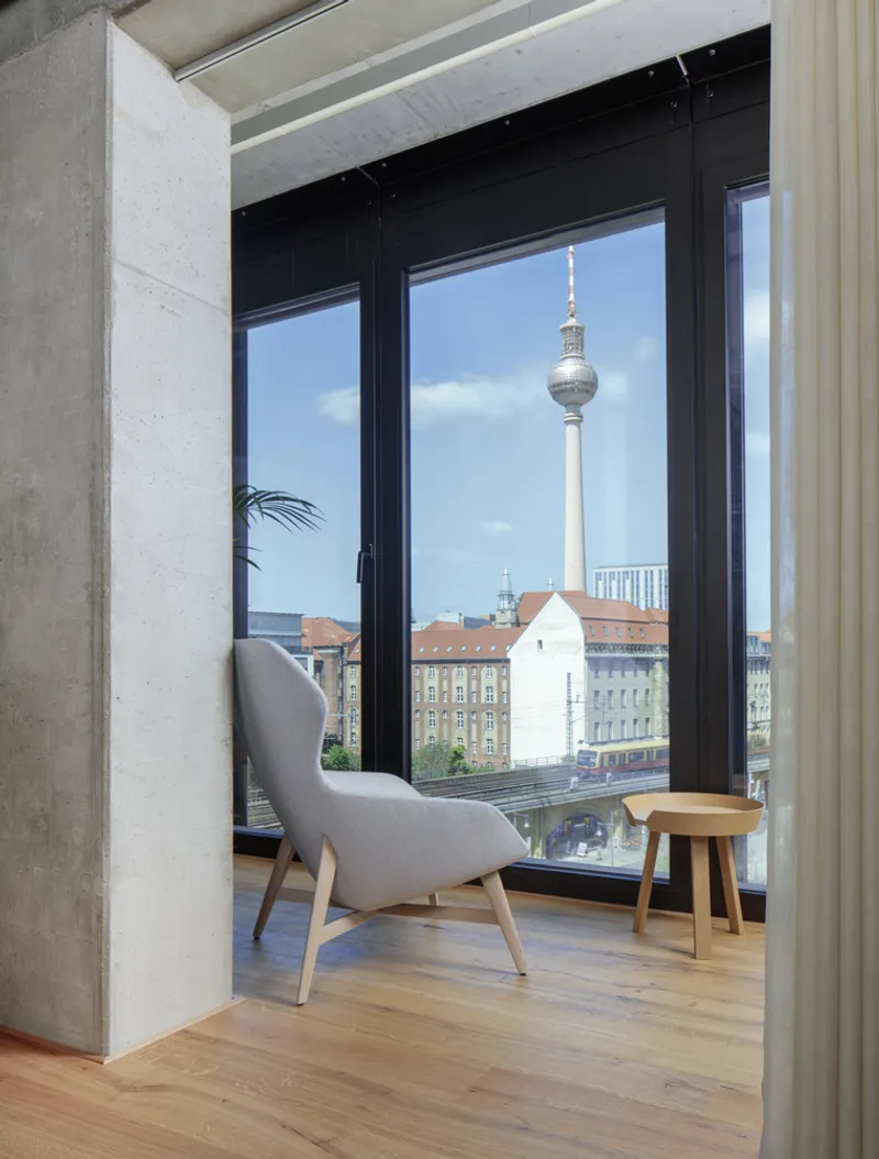 Seating alcove with concrete walls framing a black-framed window overlooking the tower and rooftops