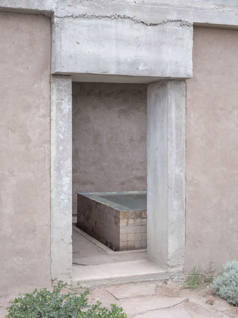 Concrete doorway framing a view of a tiled bathing basin in an interior courtyard