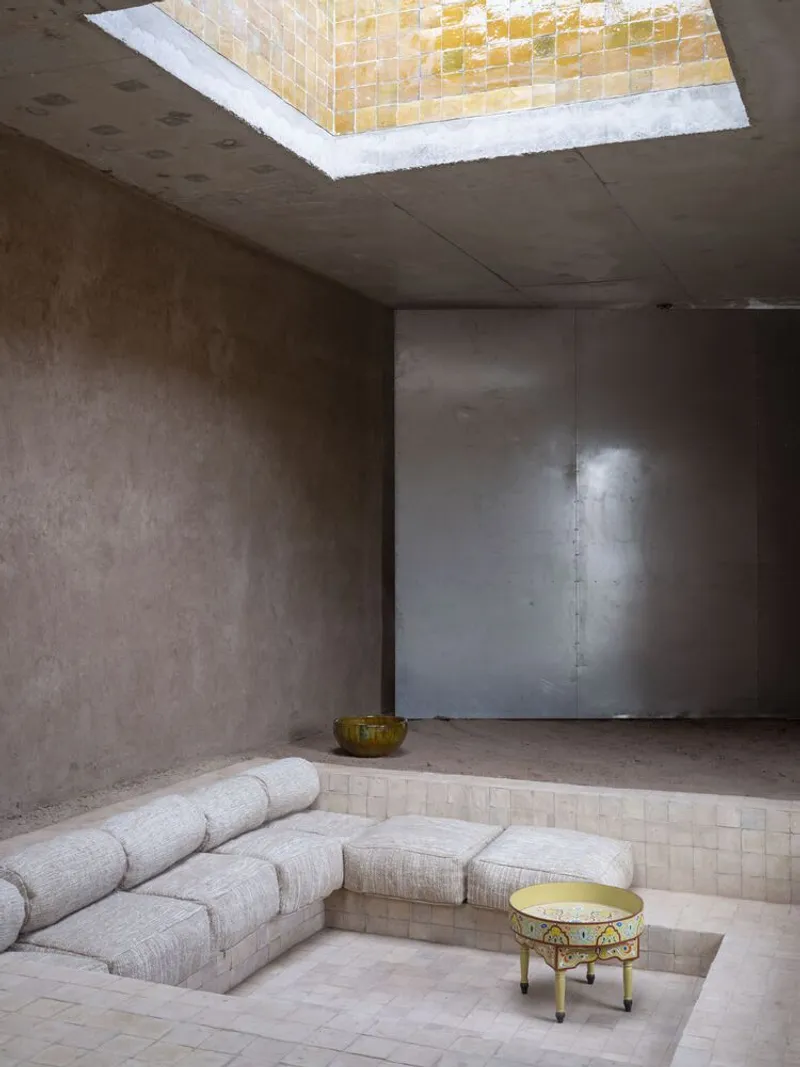 Sunken seating area with cream upholstered cushions under a golden mosaic tile skylight