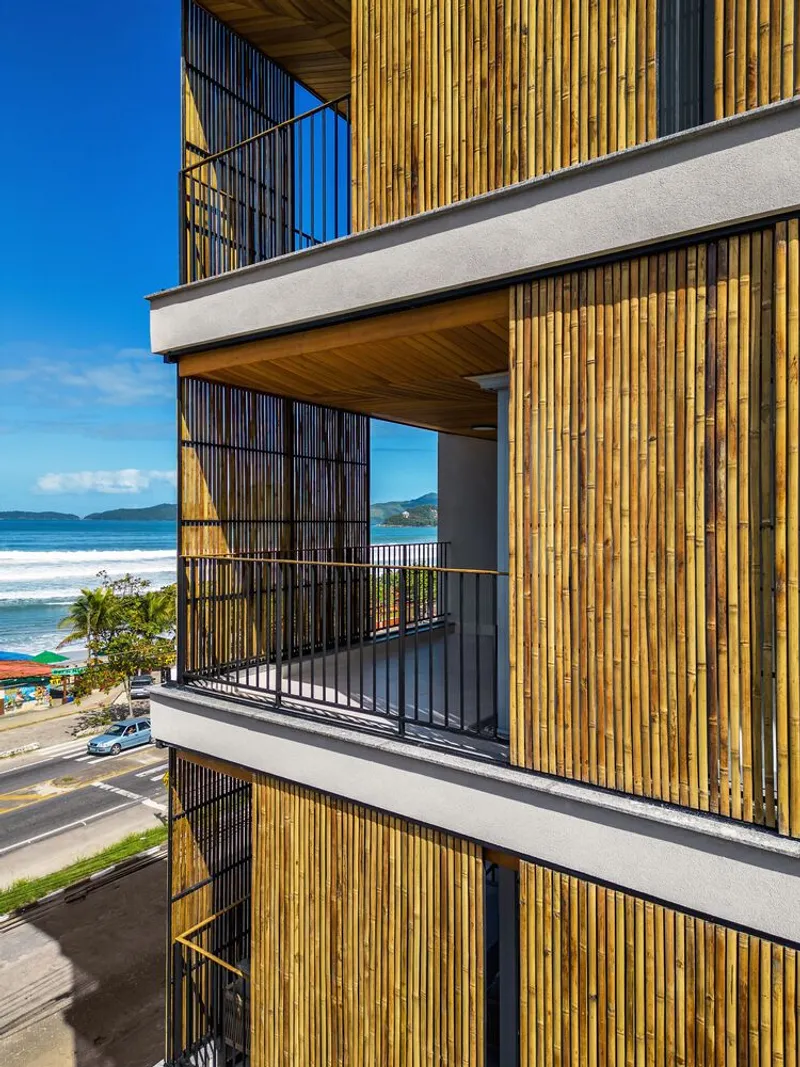 Balcony with timber screening and metal railing overlooking the ocean and coastal road in bright sunlight